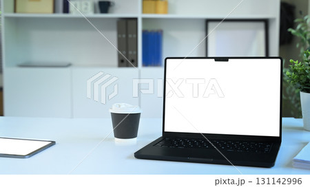 Modern workspace with a laptop, coffee cup, and tablet on a clean white desk Modern workspace with a laptop, coffee cup, and tablet on a clean white desk 131142996