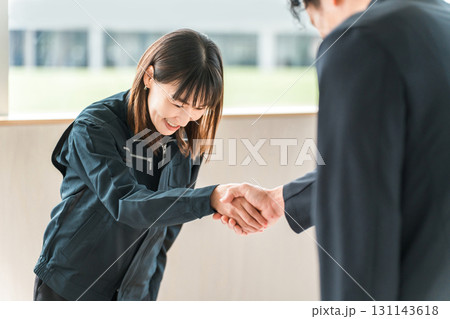 握手をする作業着姿の作業員の女性とビジネスマン 握手をする作業着姿の作業員の女性とビジネスマン 131143618