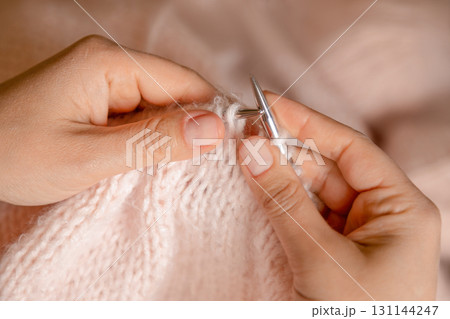 Women's hands with pink yarn and knitting needles. Woman knitting a pink sweater. Women's hands with pink yarn and knitting needles. Woman knitting a pink sweater. 131144247