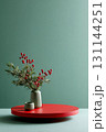 Round red podium with green background showcasing festive arrangement of red berries and greenery 131144251
