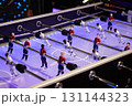 Foosball table with colorful players engaged in an exciting match under bright lights 131144323