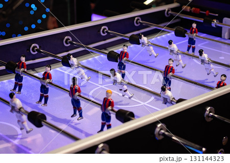 Foosball table with colorful players engaged in an exciting match under bright lights Foosball table with colorful players engaged in an exciting match under bright lights 131144323