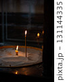 Lit church candles in sand tray, symbolic prayer and remembrance in dim sacred space 131144335