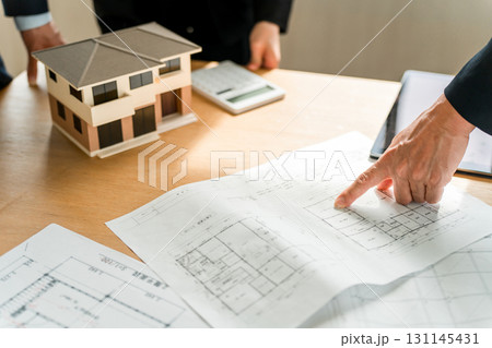 住宅模型,設計図の前で会議,ミーティングをするビジネスマン 131145431