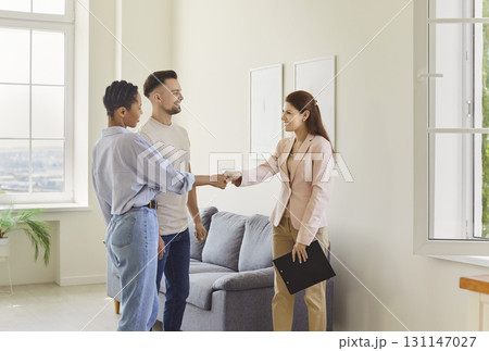 Real estate agent, female realtor meets client couple to deal, show, present new property, shaking 131147027