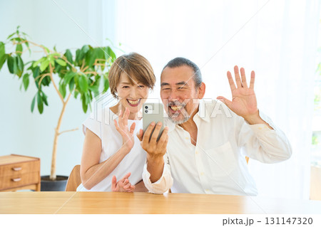 スマホでテレビ電話をする熟年夫婦 スマホでテレビ電話をする熟年夫婦 131147320