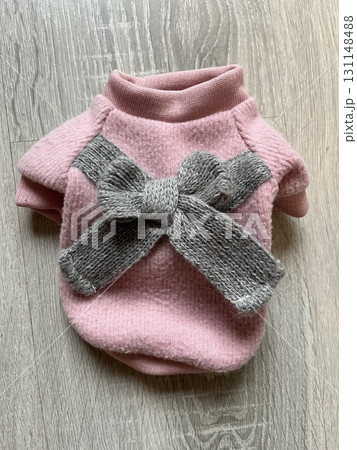Pink dog sweater with grey knitted bow on wooden surface Pink dog sweater with grey knitted bow on wooden surface 131148488