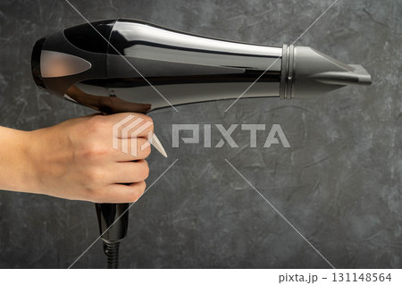 Hand holding black hair dryer for hairstyling Hand holding black hair dryer for hairstyling 131148564
