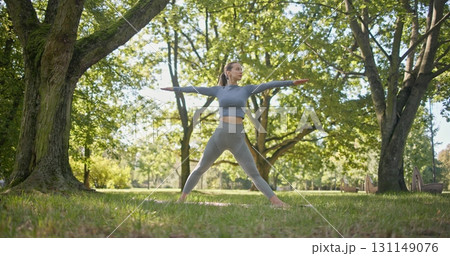 young beautiful white girl doing yoga in park among trees in clearing on summer day young beautiful white girl doing yoga in park among trees in clearing on summer day 131149076