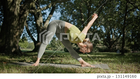 young beautiful white girl doing yoga in park among trees in clearing on summer day 131149160