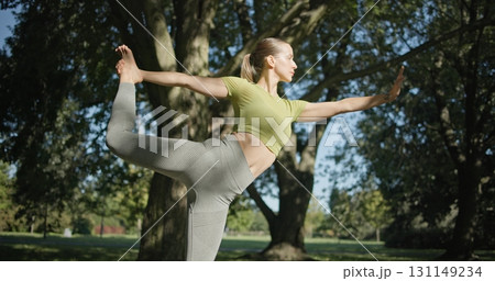 young beautiful white girl doing yoga in park among trees in clearing on summer day 131149234