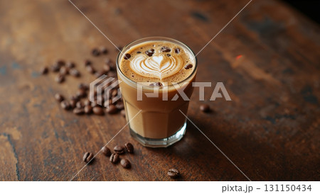 A cup of coffee with a heart design on top sits on a wooden table 131150434