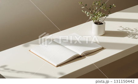 A book is open on a table next to a potted plant 131150442