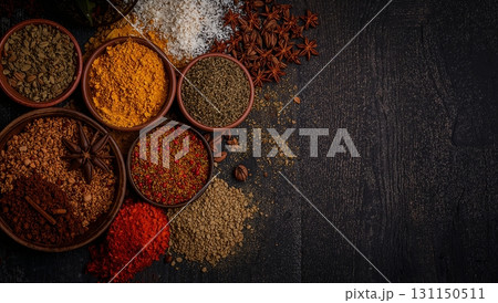 A variety of spices are displayed in bowls on a dark background 131150511