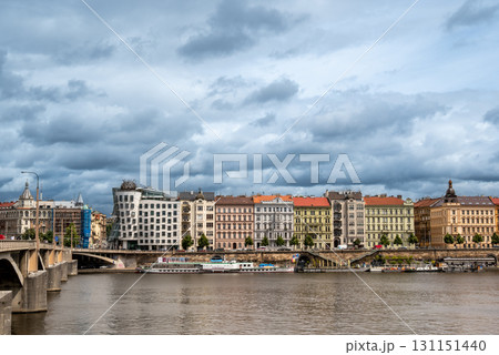 Prague, Czech Republic, August 7, 2023. Panoramic shot of the Dancing House along the Vltava River: futuristic shapes and modern materials alongside colorful historic buildings. Travel destinations. Prague, Czech Republic, August 7, 2023. Panoramic shot of the Dancing House along the Vltava River: futuristic shapes and modern materials alongside colorful historic buildings. Travel destinations. 131151440