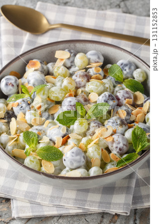 Freshly made grape salad with almonds and brown sugar sprinkled on top with creamy cheese dressing closeup in the plate. Vertical 131152853