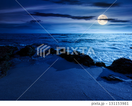 beach with sand at night. summer vacation at the seaside. beautiful seascape with calm waves in full moon light. landscape at the sea under sky with fluffy clouds 131153981