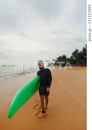 Surfer holding surf board on the beach at sunset. Happy man guy having fun doing extreme sport Surfer holding surf board on the beach at sunset. Happy man guy having fun doing extreme sport 131153993