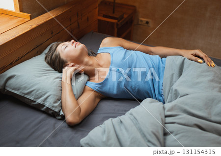 A woman is peacefully resting on a comfortable bed in a serene and calming environment while embracing tranquility 131154315