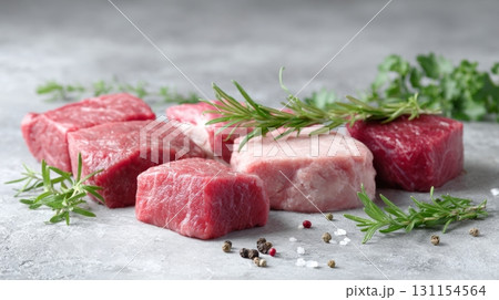 Fresh cuts of meat arranged on a gray surface with herbs and spices showcasing culinary potential Fresh cuts of meat arranged on a gray surface with herbs and spices showcasing culinary potential 131154564