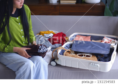 Young Asian women folding clothes, packing luggage for holiday trip. Young Asian women folding clothes, packing luggage for holiday trip. 131154583