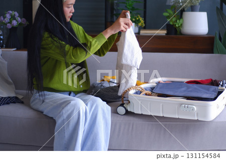 Young Asian women folding clothes, packing luggage for holiday trip. Young Asian women folding clothes, packing luggage for holiday trip. 131154584