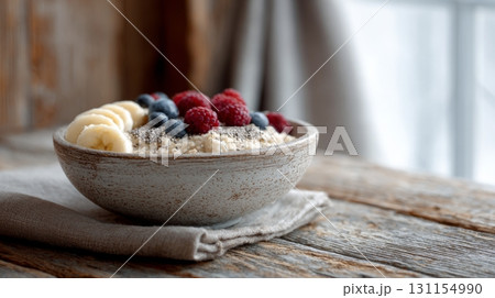 A colorful bowl of oatmeal topped with fruits sits on a rustic table, emphasizing healthy eating choices 131154990