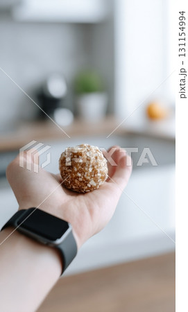 Hand showcases a nutritious snack while wearing a smartwatch in a bright kitchen setting 131154994