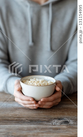 Hands hold a bowl of cereal, highlighting a focus on high fiber foods for wellness 131154995
