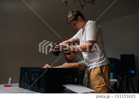 Two technicians male working together, one taking pictures with digital camera while other holding computer case open during maintenance or repair session. Concept of desktop PC upgrade and service. Two technicians male working together, one taking pictures with digital camera while other holding computer case open during maintenance or repair session. Concept of desktop PC upgrade and service. 131155025
