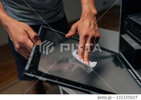 Closeup hands of unrecognizable computer technician wiping glass panel, clearing dust buildup and improving internal airflow for enhanced electronic system performance. Concept of service, cleaning PC Closeup hands of unrecognizable computer technician wiping glass panel, clearing dust buildup and improving internal airflow for enhanced electronic system performance. Concept of service, cleaning PC 131155027