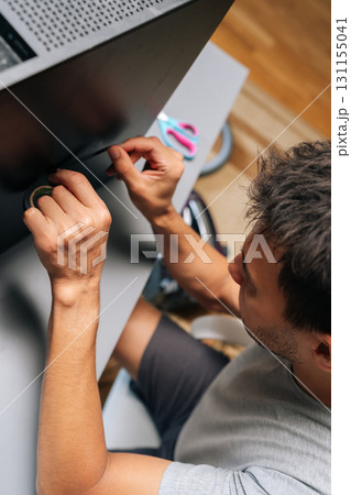 Vertical top view of technician applying black electrical tape while performing computer case repair, showing diy troubleshooting technique at workshop. Concept of desktop PC maintenance and service. Vertical top view of technician applying black electrical tape while performing computer case repair, showing diy troubleshooting technique at workshop. Concept of desktop PC maintenance and service. 131155041