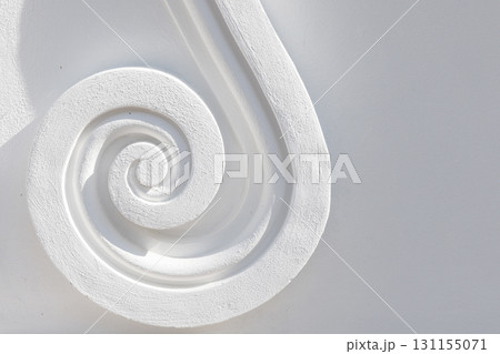 A close-up of a carved white spiral molding, showcasing smooth curve texture A close-up of a carved white spiral molding, showcasing smooth curve texture 131155071