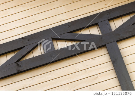 A dark black wooden truss laid over light-toned wooden planks, wall decor 131155076