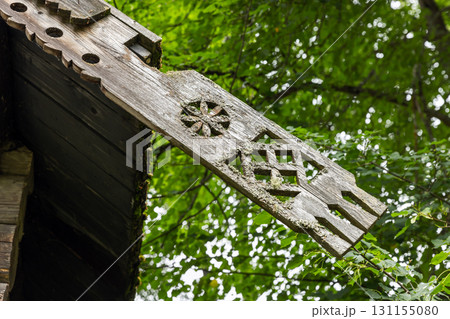 A weathered, intricately carved wooden beam ornament sits on a rustic roof 131155080
