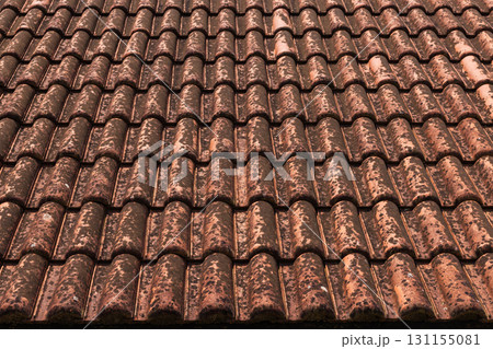 Perspective view of an old terracotta roof tiles showing patina and rust marks 131155081