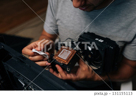 Precise computer maintenance involving cleaning processor cooling system, wiping delicate electronic components with white microfiber cloth for peak hardware performance at workshop. 131155113