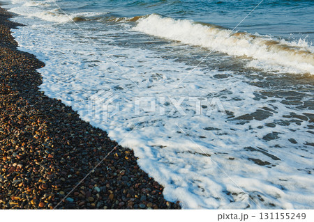 Serene waves gently crash on a pebbled beach at sunrise, capturing a peaceful moment by the sea Serene waves gently crash on a pebbled beach at sunrise, capturing a peaceful moment by the sea 131155249