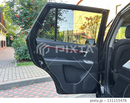 Open car door revealing a quiet neighborhood street lined with trees and vibrant flowers during the early evening light Open car door revealing a quiet neighborhood street lined with trees and vibrant flowers during the early evening light 131155476