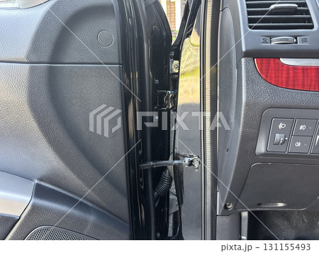 Car door hinges reveal intricate engineering details at a sunny afternoon home parking space Car door hinges reveal intricate engineering details at a sunny afternoon home parking space 131155493