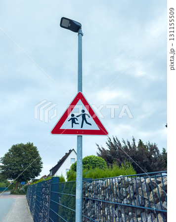 Caution sign marking children's crossing area near residential street on a cloudy day Caution sign marking children's crossing area near residential street on a cloudy day 131155509