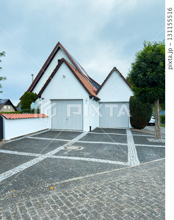 Modern house with unique architecture and double garage situated on a quiet residential street in the morning 131155516