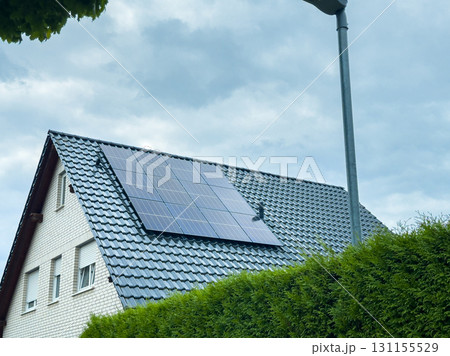 Solar panels installed on a modern home roof in a suburban neighborhood under a cloudy sky 131155529
