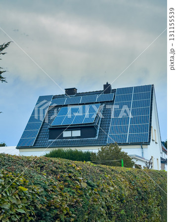 Solar panels cover a modern house roof in a quiet neighborhood showcasing sustainable energy solutions for residential living 131155539