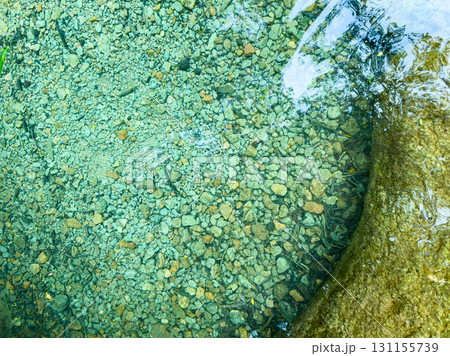 Crystal clear water reveals smooth stones and pebbles in a serene natural setting, captured during bright daylight in a tranquil forest stream Crystal clear water reveals smooth stones and pebbles in a serene natural setting, captured during bright daylight in a tranquil forest stream 131155739