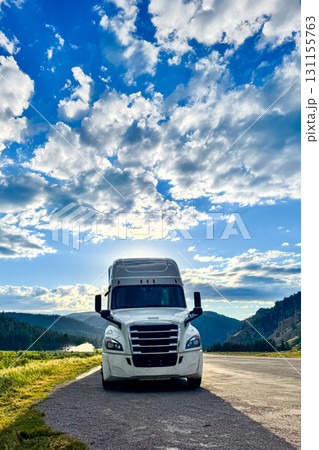 Transporting dreams on a long, winding road through scenic landscapes under a sky full of fluffy clouds at sunset Transporting dreams on a long, winding road through scenic landscapes under a sky full of fluffy clouds at sunset 131155763