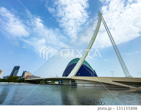 Stunning modern bridge with unique architecture over tranquil water under a bright blue sky in a vibrant city Stunning modern bridge with unique architecture over tranquil water under a bright blue sky in a vibrant city 131155806