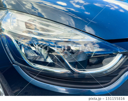 Bright blue car headlight reflects fluffy clouds on a sunny day, showcasing perfect vehicle craftsmanship and nature's beauty 131155816