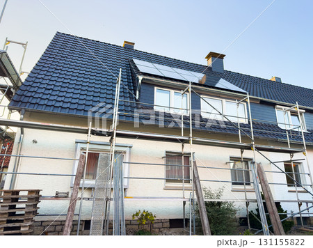 Roof renovation occurs on a residential building with scaffolding in a suburban neighborhood during daylight hours Roof renovation occurs on a residential building with scaffolding in a suburban neighborhood during daylight hours 131155822