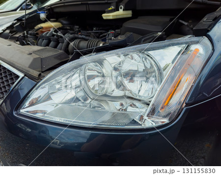 Close-up view of a car headlight showcasing its design features and intricate details in a parking lot during the afternoon Close-up view of a car headlight showcasing its design features and intricate details in a parking lot during the afternoon 131155830